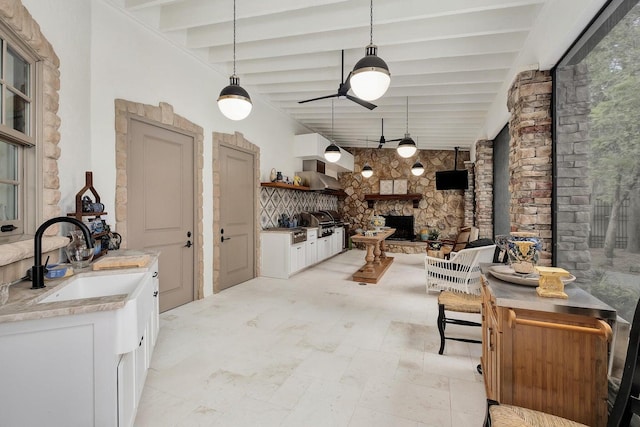 kitchen with ceiling fan, beamed ceiling, a sink, and white cabinets