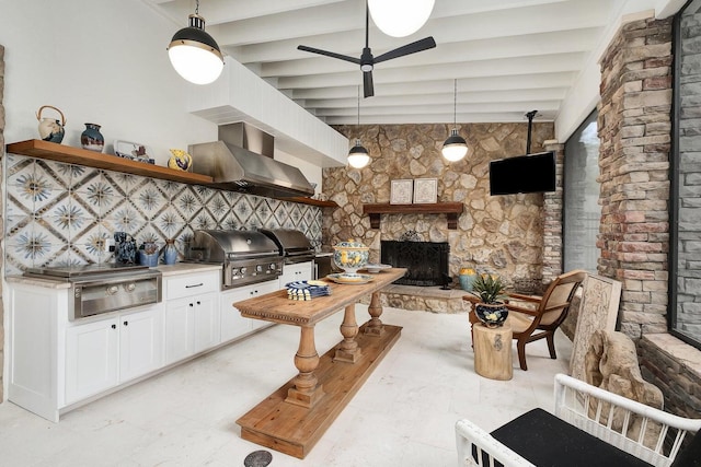 kitchen with open shelves, white cabinetry, a stone fireplace, wall chimney range hood, and beamed ceiling