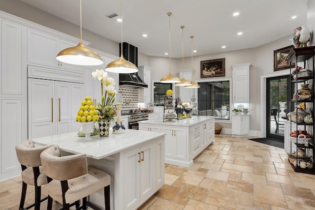 kitchen featuring a center island, stone tile flooring, visible vents, white cabinetry, and high end stove