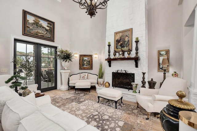 living room featuring a towering ceiling, a stone fireplace, wood finished floors, and french doors