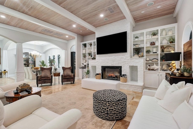 living area featuring arched walkways, wooden ceiling, a fireplace, beamed ceiling, and decorative columns