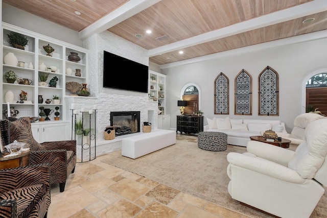 living area featuring beam ceiling, recessed lighting, stone tile flooring, wood ceiling, and a stone fireplace