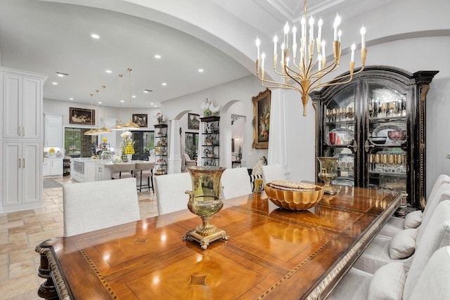 dining space with arched walkways, stone finish floor, an inviting chandelier, and recessed lighting