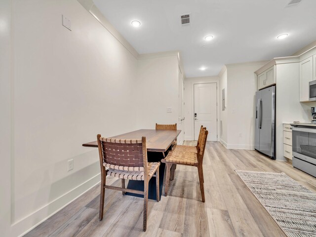 dining area with ornamental molding and light wood-type flooring