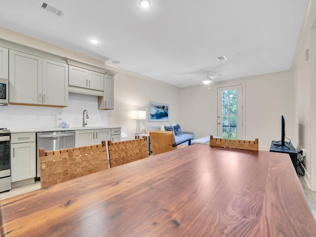 kitchen with gray cabinets, sink, backsplash, ceiling fan, and stainless steel appliances