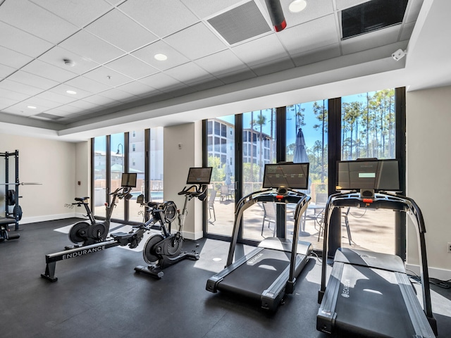 exercise room with expansive windows, a healthy amount of sunlight, and a drop ceiling