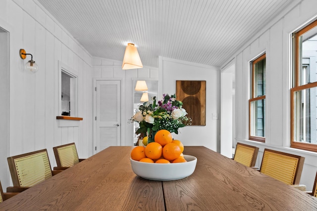 dining space with lofted ceiling and wooden walls