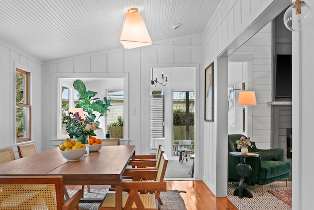 dining area with an inviting chandelier, crown molding, light hardwood / wood-style flooring, and vaulted ceiling