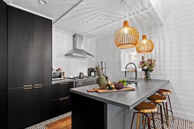 kitchen featuring wall chimney exhaust hood, kitchen peninsula, a breakfast bar area, and stainless steel appliances