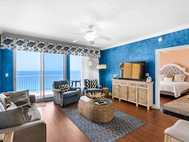 living room featuring crown molding, dark hardwood / wood-style floors, ceiling fan, and a water view