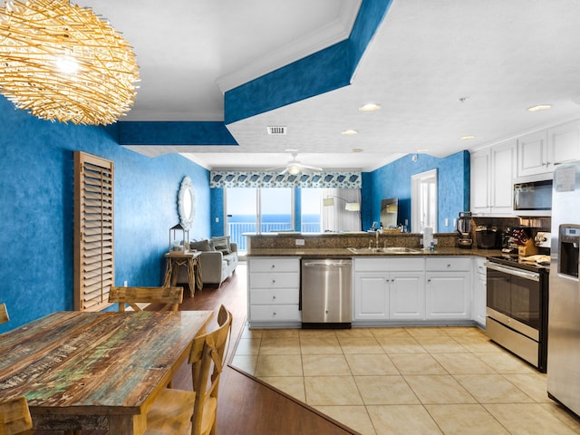 kitchen with ceiling fan, kitchen peninsula, stainless steel appliances, light tile flooring, and white cabinetry