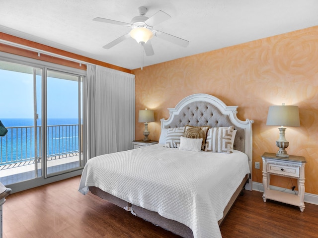 bedroom featuring multiple windows, hardwood / wood-style flooring, a water view, and access to exterior