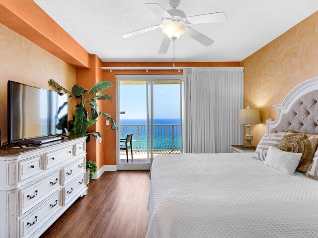 bedroom with ceiling fan, a water view, dark hardwood / wood-style flooring, and access to outside