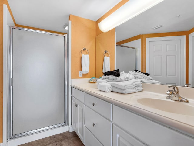 bathroom with a shower with shower door, large vanity, and tile floors