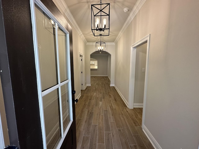 corridor featuring an inviting chandelier, wood-type flooring, and ornamental molding