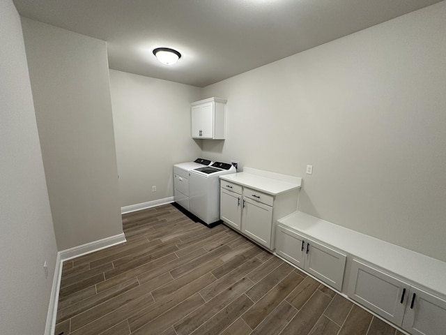 laundry area featuring separate washer and dryer, cabinets, and dark wood-type flooring