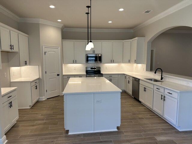 kitchen featuring white cabinetry, sink, decorative light fixtures, a kitchen island, and appliances with stainless steel finishes