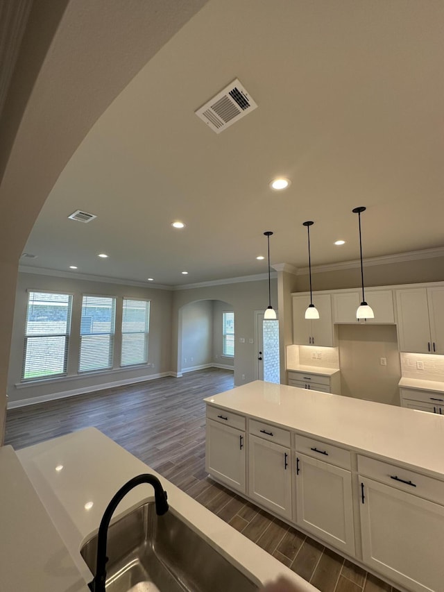 kitchen featuring decorative backsplash, ornamental molding, dark wood-type flooring, pendant lighting, and white cabinetry