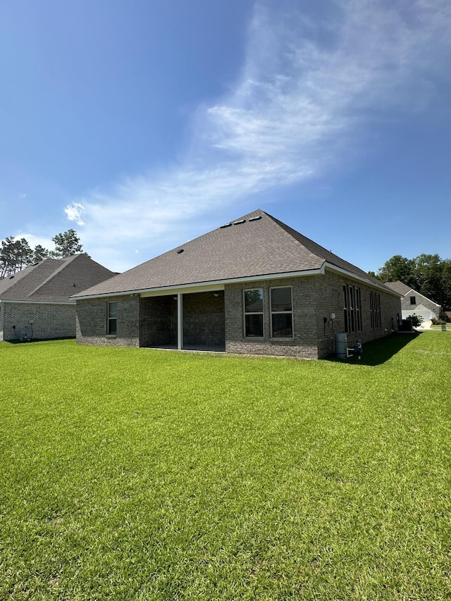 rear view of property featuring central air condition unit and a lawn