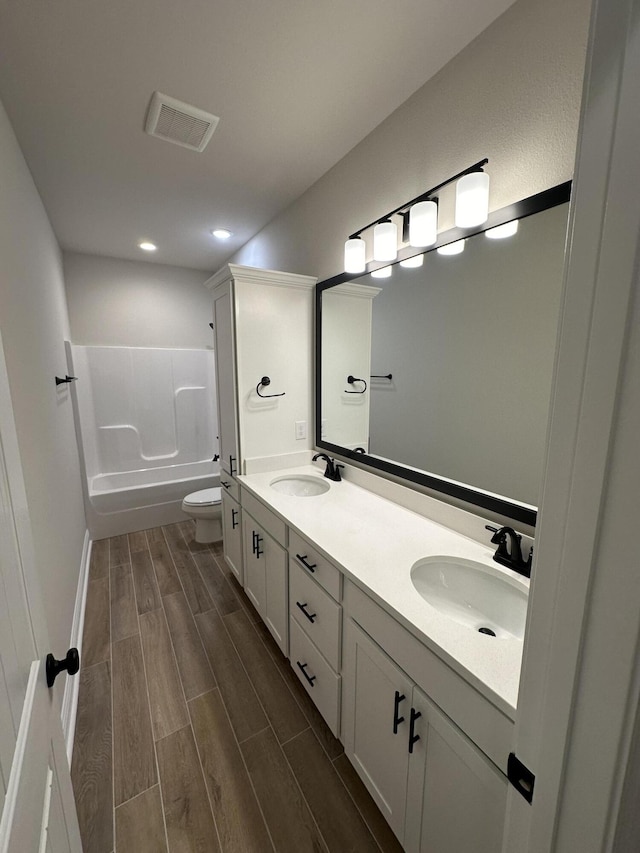 full bathroom featuring vanity, hardwood / wood-style flooring, toilet, and shower / washtub combination