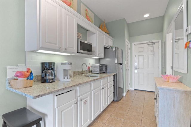 kitchen featuring stainless steel appliances, tasteful backsplash, white cabinets, sink, and light tile floors