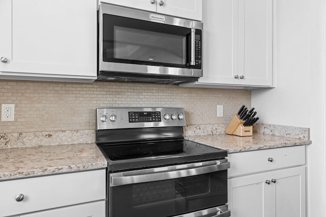 kitchen featuring light stone countertops, decorative backsplash, white cabinets, and stainless steel appliances
