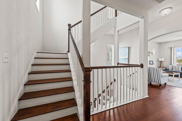 stairway with hardwood / wood-style flooring and a high ceiling