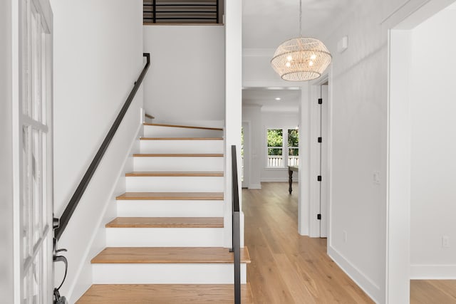 stairs featuring hardwood / wood-style floors and an inviting chandelier