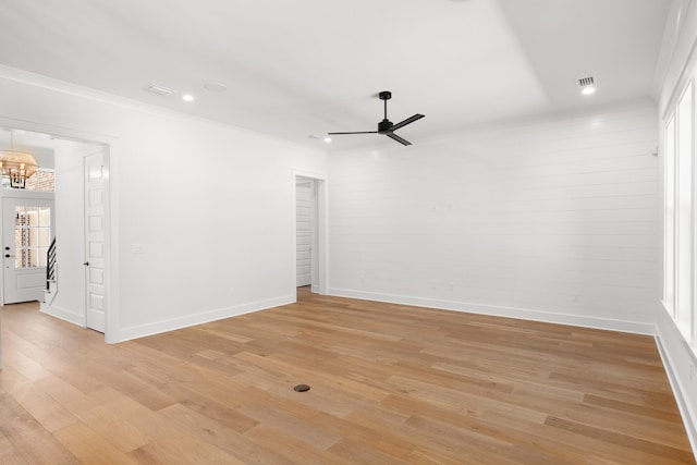 empty room with ceiling fan with notable chandelier, light wood-type flooring, and ornamental molding