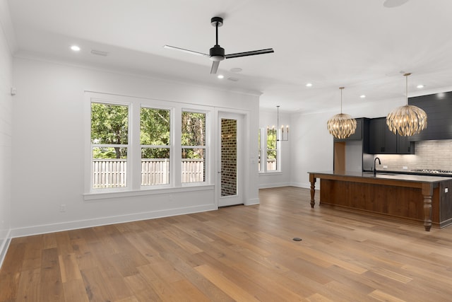 interior space with ceiling fan with notable chandelier, crown molding, and light hardwood / wood-style flooring