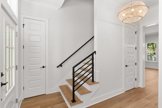 stairs with hardwood / wood-style flooring, an inviting chandelier, and ornamental molding