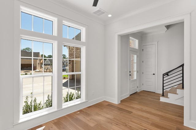 entryway with a healthy amount of sunlight, light hardwood / wood-style floors, and ornamental molding