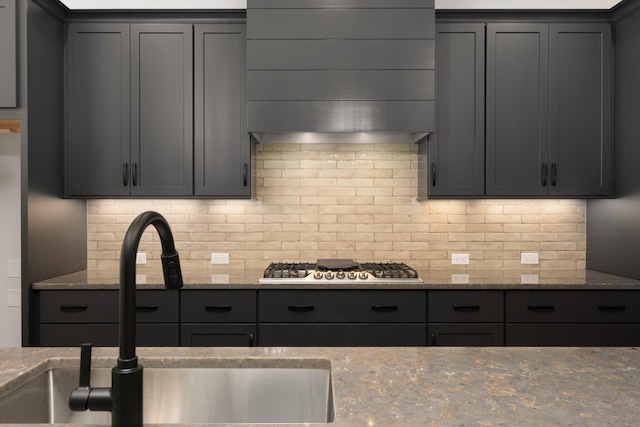 kitchen featuring light stone countertops, tasteful backsplash, and sink