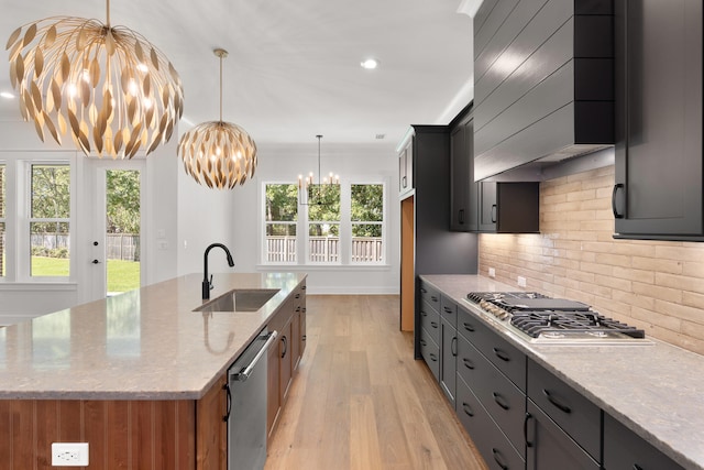 kitchen with sink, stainless steel appliances, an inviting chandelier, light stone counters, and light hardwood / wood-style floors