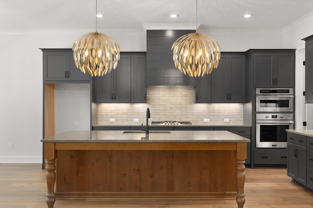 kitchen featuring light hardwood / wood-style flooring, stainless steel appliances, an island with sink, and a chandelier