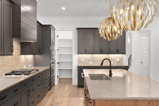 kitchen with decorative backsplash, light stone counters, stainless steel appliances, sink, and light hardwood / wood-style floors