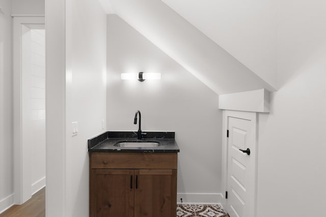 bathroom with hardwood / wood-style floors, vanity, and vaulted ceiling