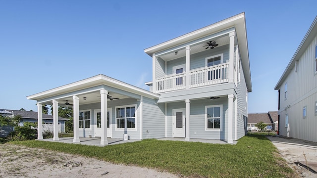 view of front of home with ceiling fan, a balcony, and a front lawn