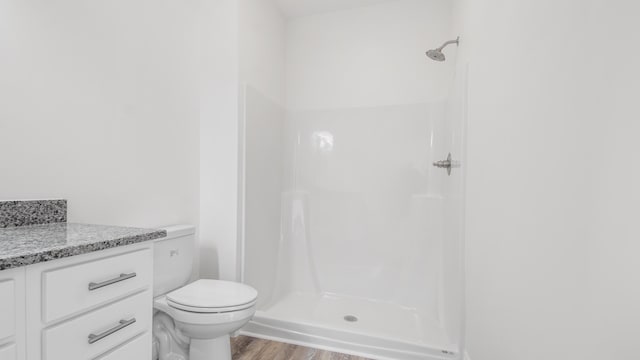 bathroom with a shower, vanity, hardwood / wood-style flooring, and toilet