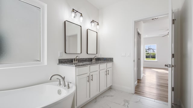 bathroom featuring a tub, ceiling fan, and vanity