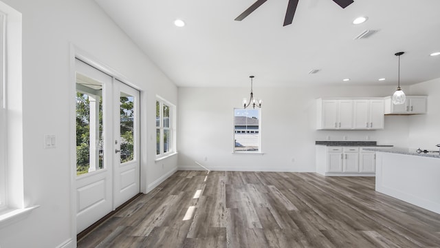 interior space featuring white cabinets, pendant lighting, ceiling fan with notable chandelier, and dark hardwood / wood-style floors