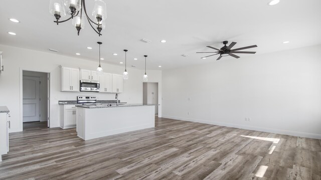 kitchen featuring pendant lighting, ceiling fan with notable chandelier, an island with sink, appliances with stainless steel finishes, and white cabinetry