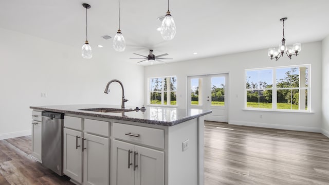 kitchen with dishwasher, sink, hanging light fixtures, a center island with sink, and ceiling fan with notable chandelier