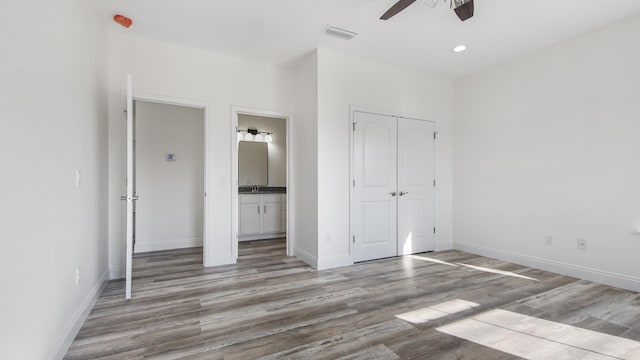 unfurnished bedroom with connected bathroom, ceiling fan, and light wood-type flooring