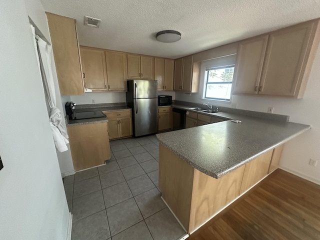 kitchen with light brown cabinetry, sink, light tile patterned floors, kitchen peninsula, and stainless steel appliances