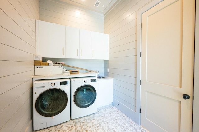 laundry room with cabinets, wood walls, and washing machine and clothes dryer