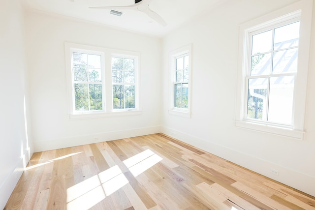 empty room with ceiling fan, a healthy amount of sunlight, crown molding, and light hardwood / wood-style flooring