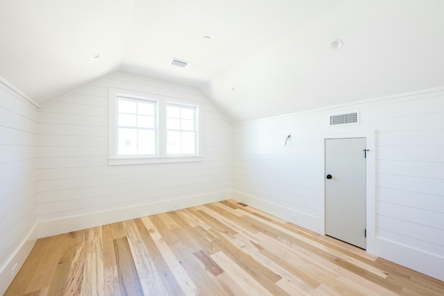 bonus room with light hardwood / wood-style floors, lofted ceiling, and wood walls