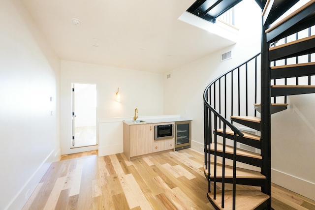 stairway featuring hardwood / wood-style floors, beverage cooler, and sink