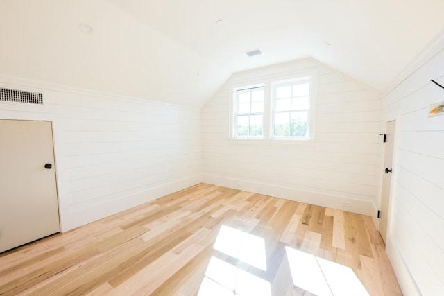 additional living space with hardwood / wood-style flooring, wood walls, and lofted ceiling